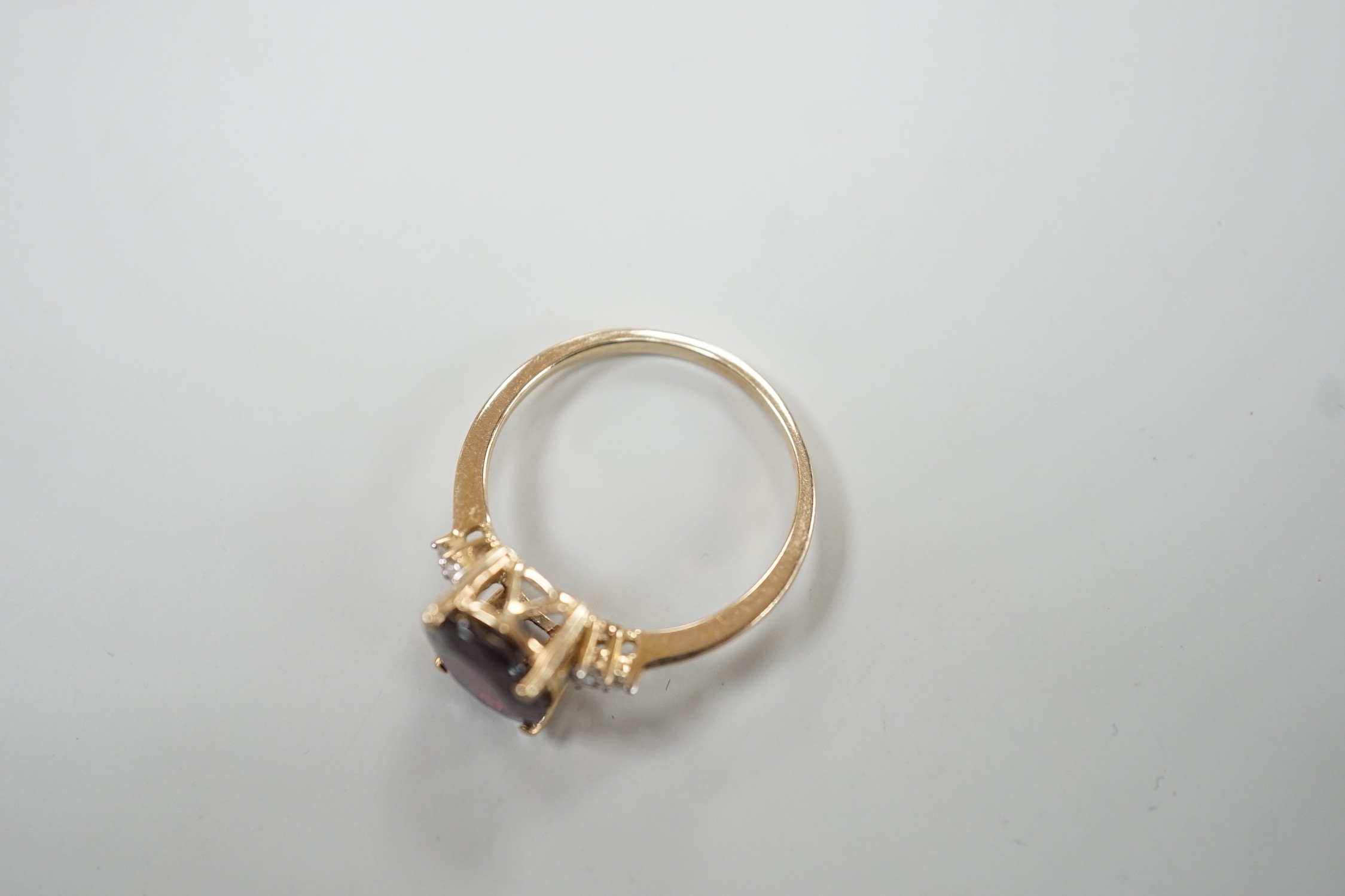 A modern 9ct gold, single stone oval cut garnet and six stone diamond chip set dress ring, size R/S, gross weight 2.8 grams.
